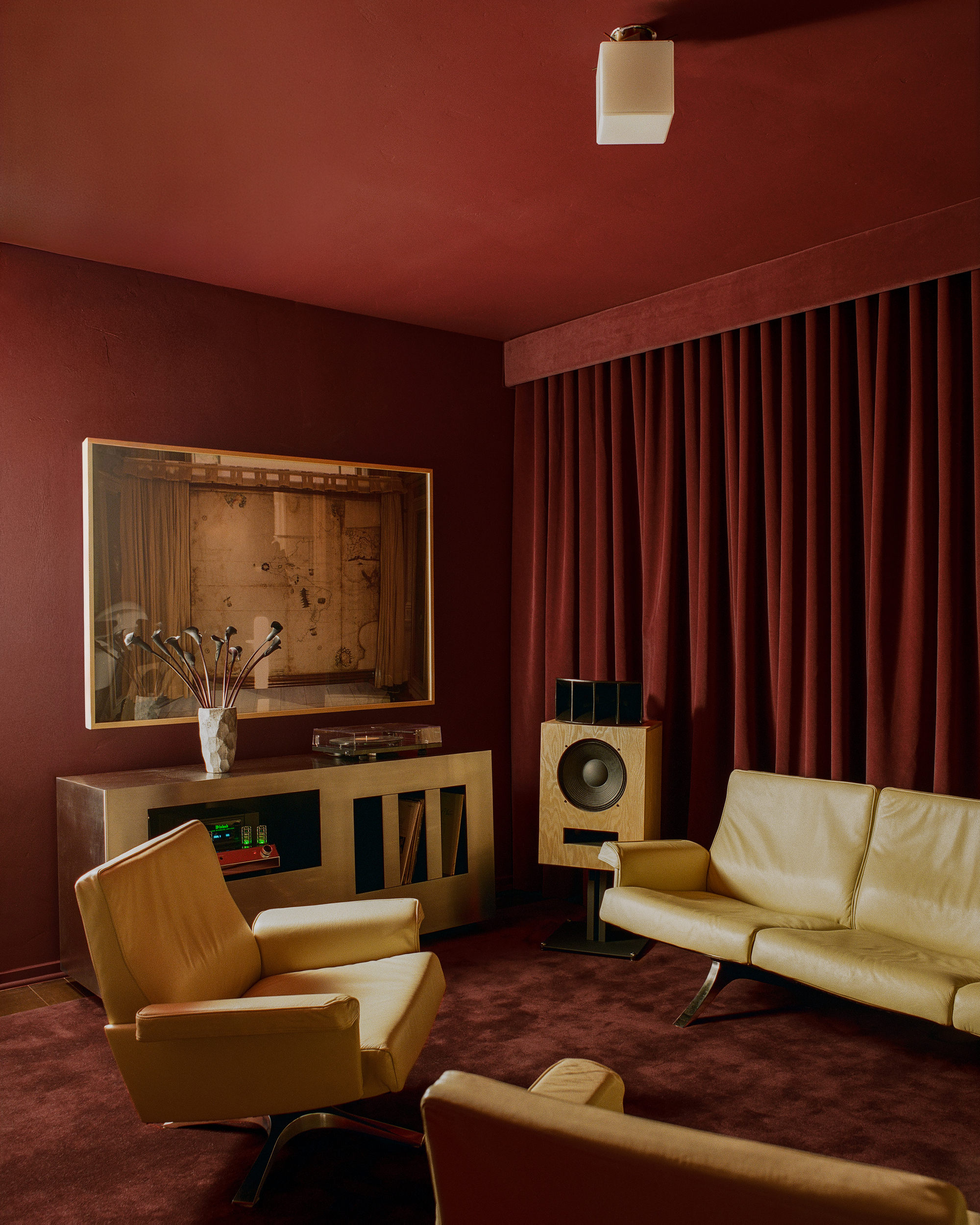 Image of a red, color-drenched living room/listening room with butter yellow leather seating. There is a golden record console cabinet and a large speaker.