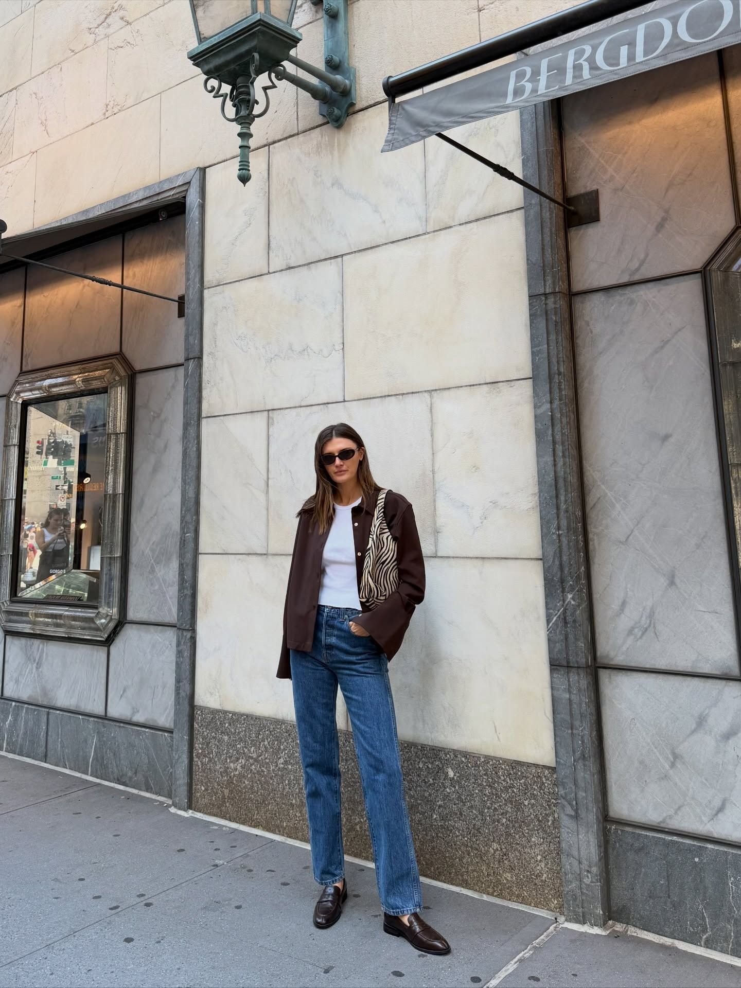 @cocoschiffer wearing a white T-shirt and jeans outfit with a chore jacket, animal print bag, and loafers