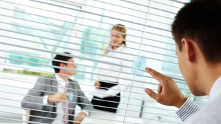 man spying on business meeting room through blinds
