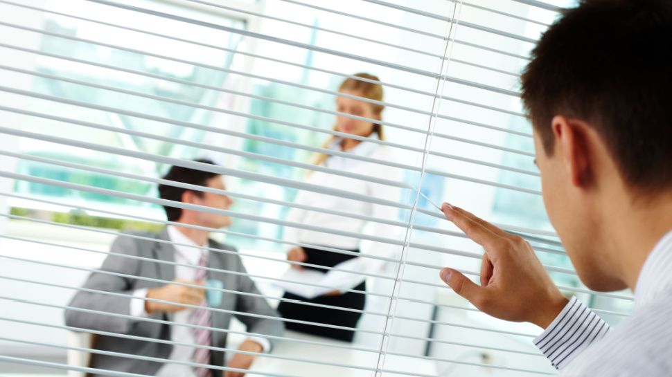 man spying on business meeting room through blinds