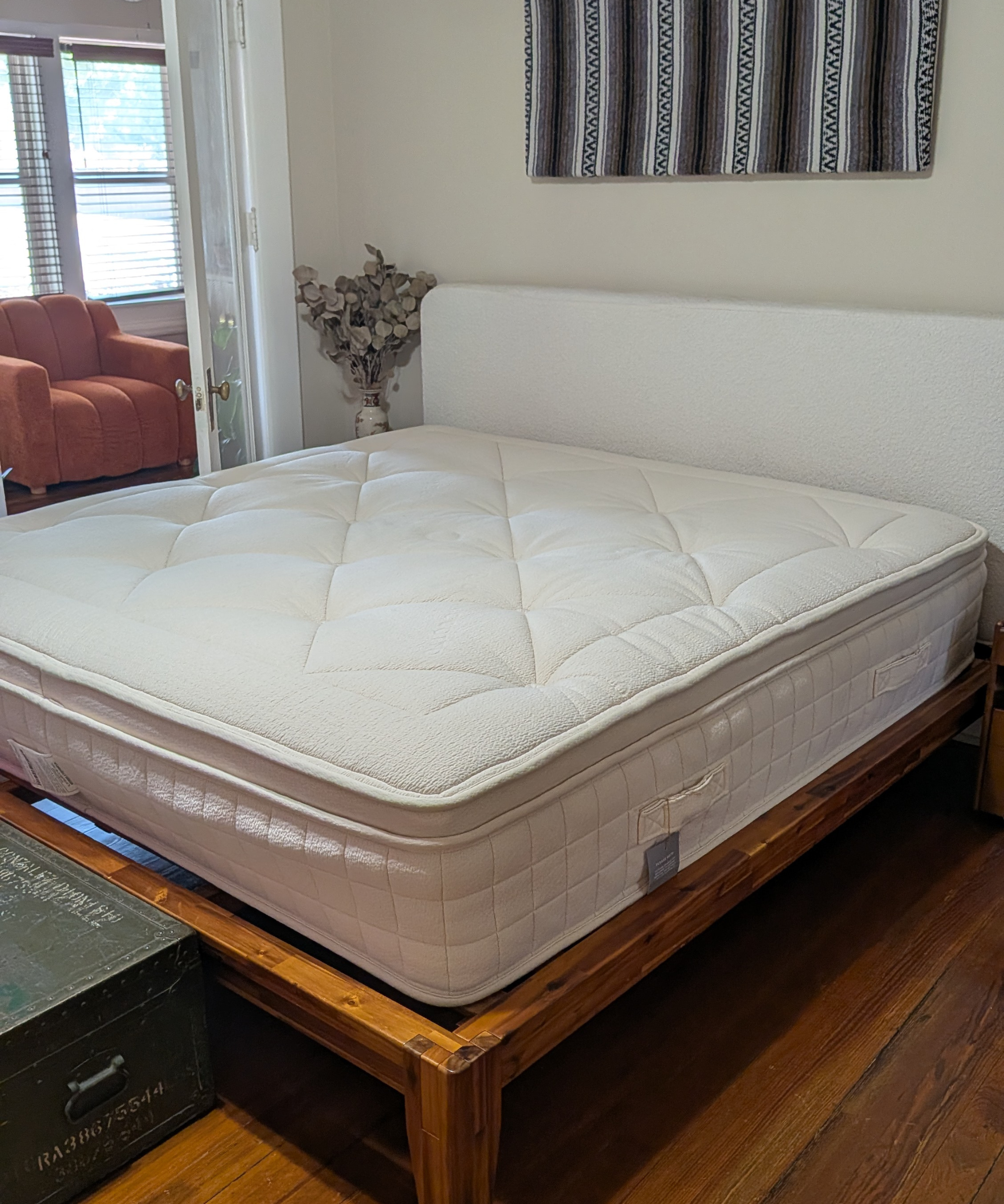 Avocado Luxury Organic Mattress sits on a bed frame unmade.