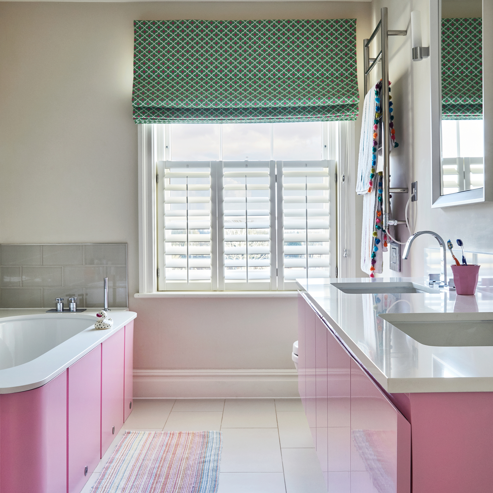 Bathroom with pink cabintery, white shutters and patterned blinds