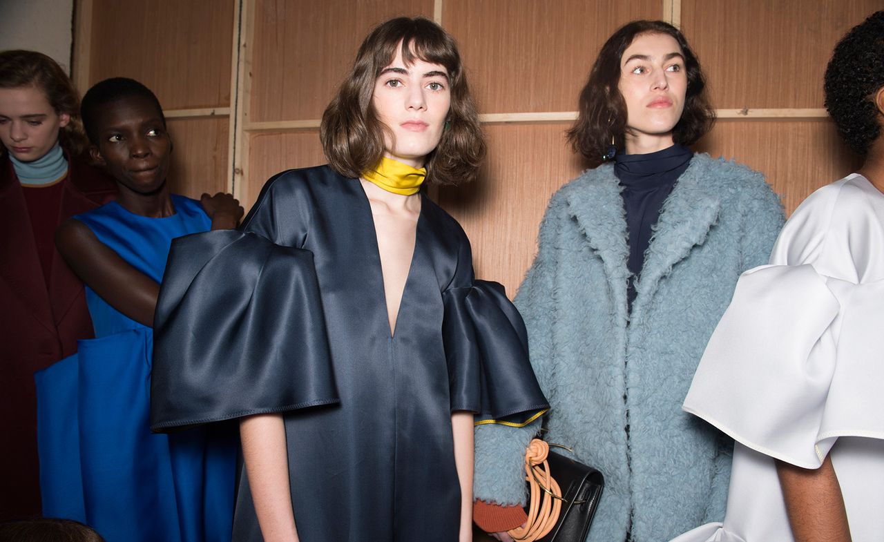 Model wears a navy V-neck blouse with exaggerated balloon sleeves, another wears an oversized light-blue teddy coat