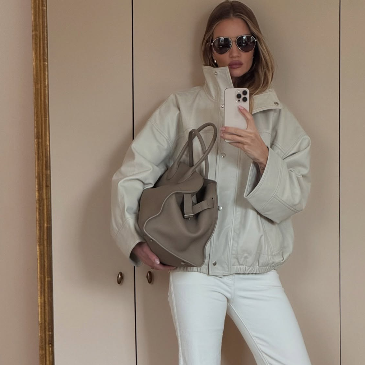 Celeberity Rosie HW wears a off-white bomber jacket, white jeans, The Row Margaux and oval sunglasses in a recent image taken from her Instagram. 