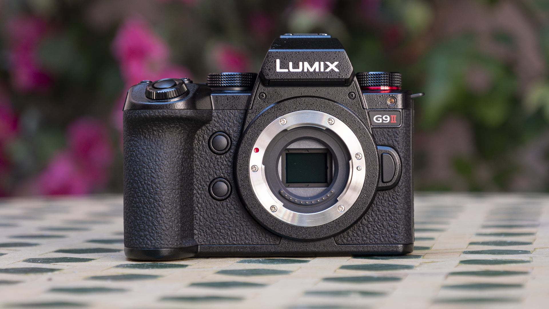 Panasonic Lumix G9 II camera on a patterned table with pink flower background