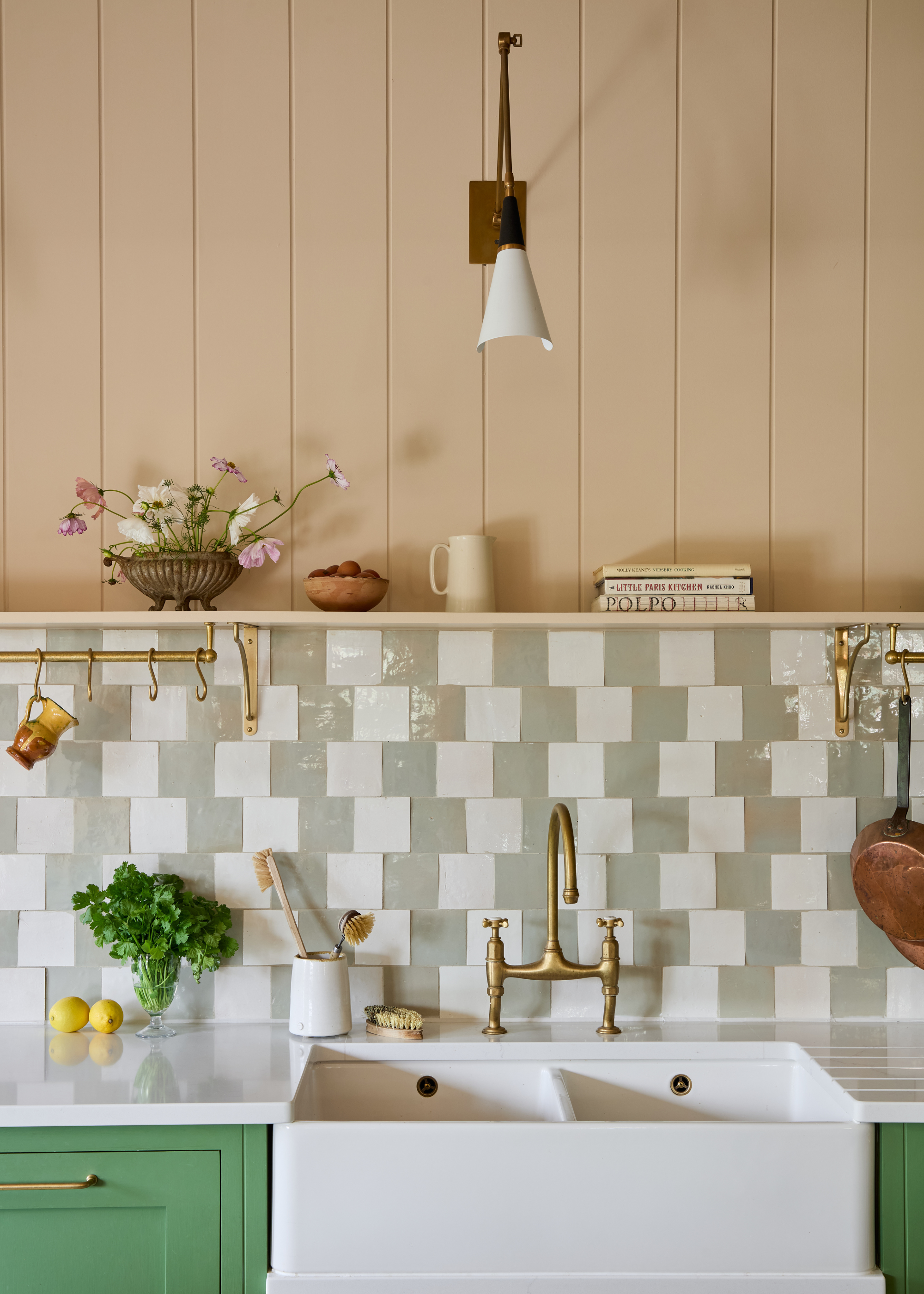A modern traditional double farmhouse kitchen sink with modern patterned tiles as the backsplash in light gray and white and light pink wood panelling above with an open shelf between them