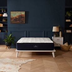 The DreamCloud Luxury Hybrid mattress in a bedroom with dark walls