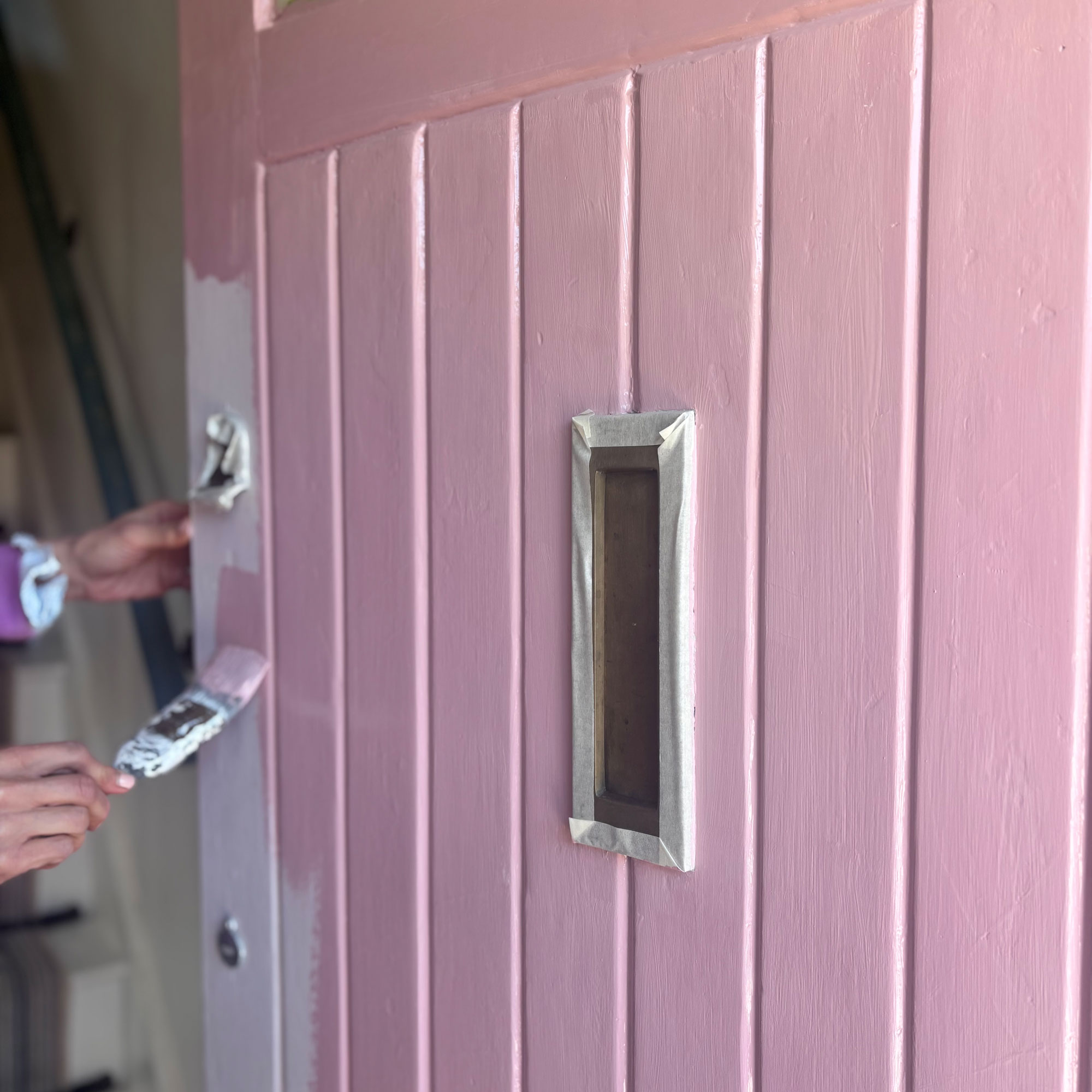 painting a front door pink with a paintbrush