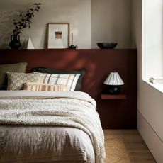 bedroom with deep red wall and bed with cushions and pillows