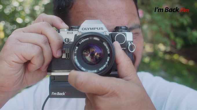 I&#039;m Back Film 2023 attached to an Olympus SLR camera in photographer&#039;s hands