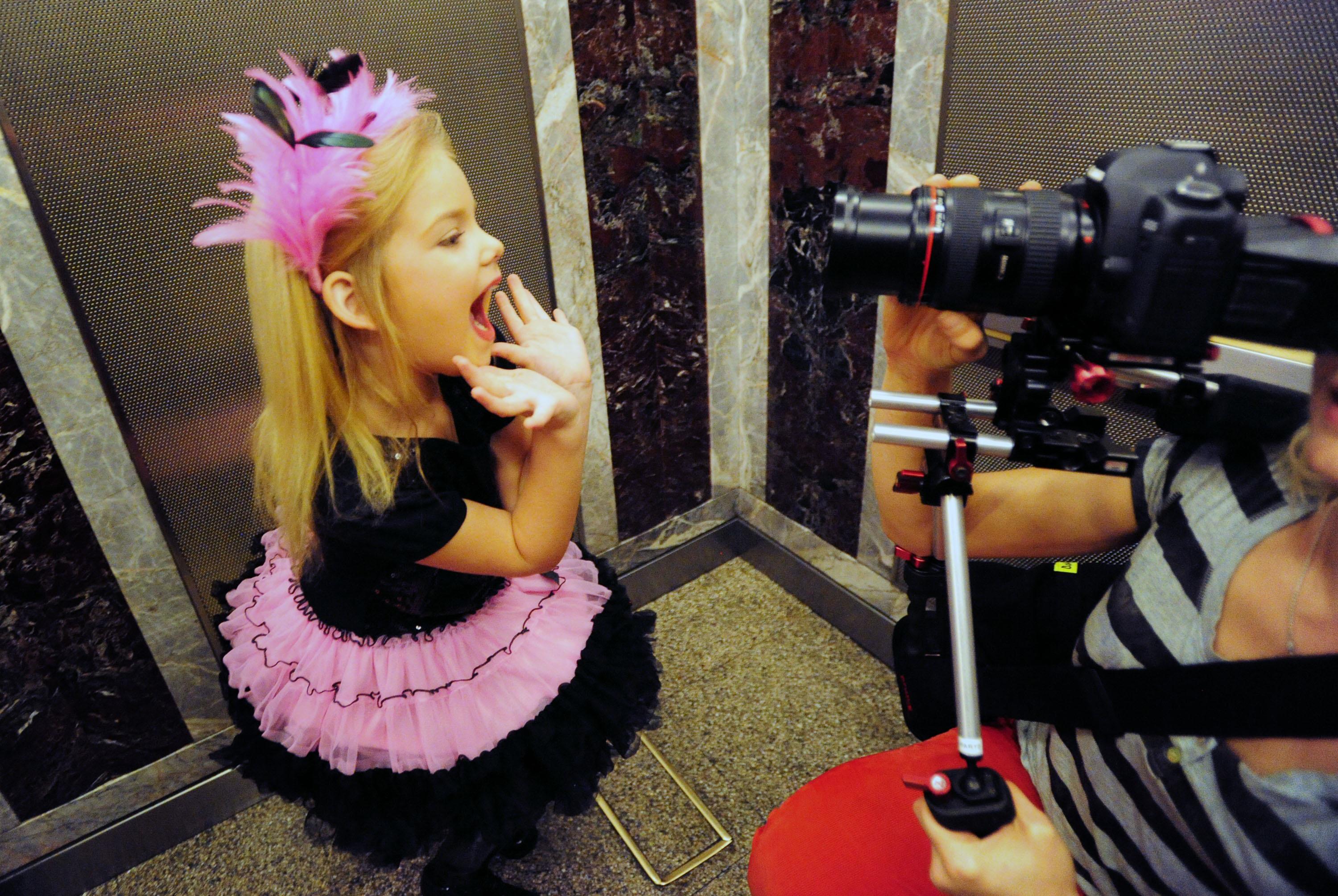 a little girl in a pink crown and tutu waving to a camera in 'Toddlers and Tiaras'