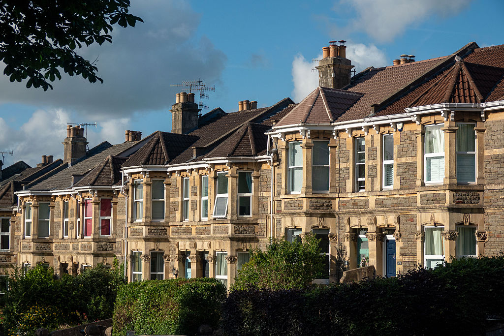 Sunlight illuminates the front of a row of Victorian-era houses on a terraced street