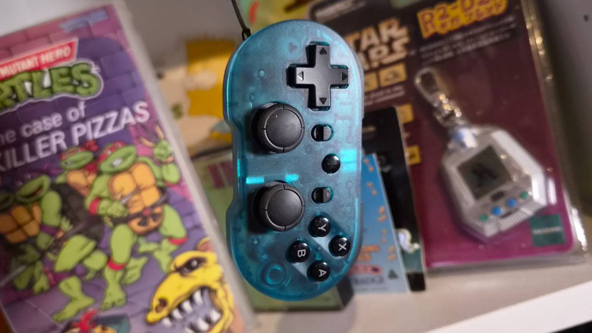Photo of the CRKD Atom+ controller dangling in front of a shelf.