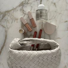 Bottega bag with makeup products from Rose Inc and a Byredo perfume bottle