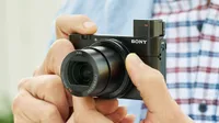The Sony Cyber-shot RX100 IV being held in two hands with its viewfinder popped open