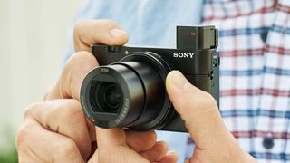 Henkilö pitää kädessään Sony Cyber-shot RX100 IV -kameraa