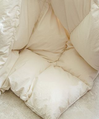 The corner of a white baffle box style comforter folded onto a gray surface