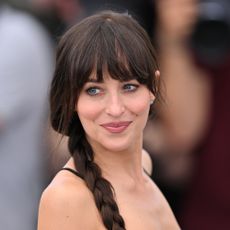 Dakota Johnson looks away from the camera wearing a side braid