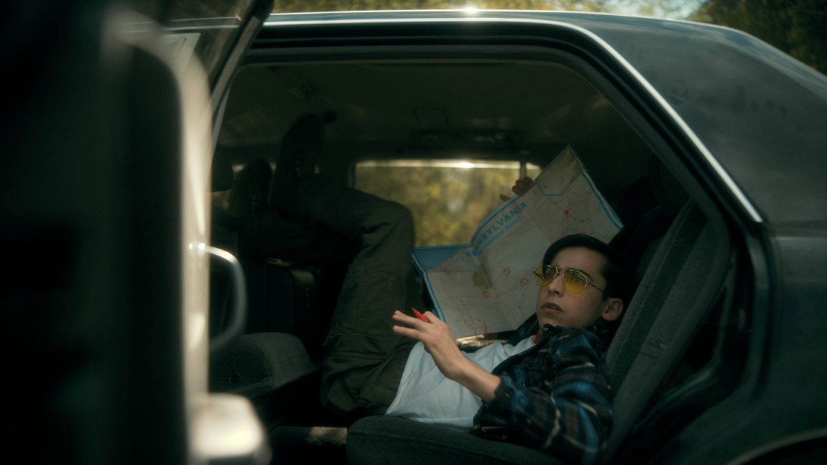 Five Hargreeves sits awkwardly in the back of a car in The Umbrella Academy season 3