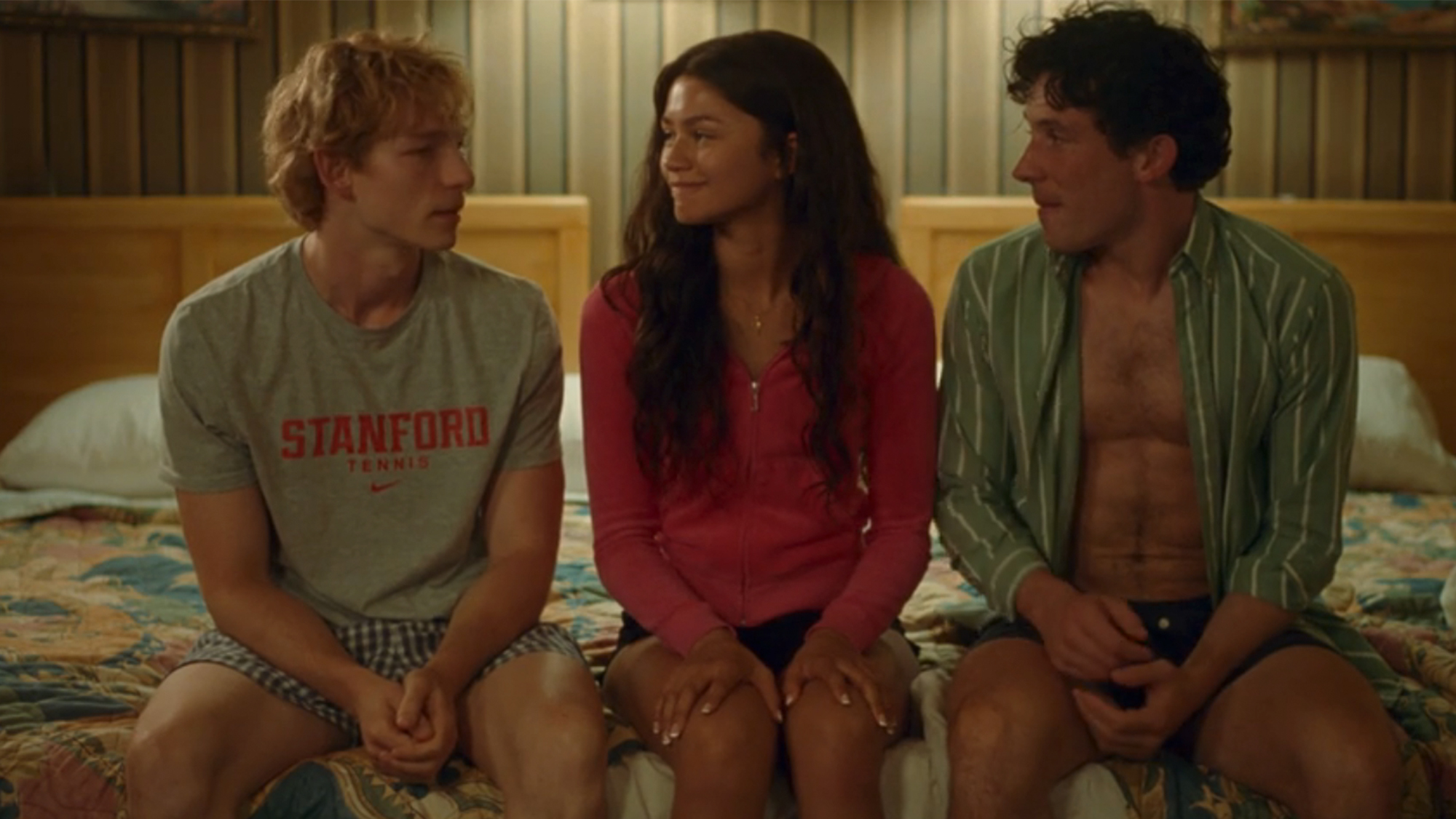 Zendaya sitting on a bed between Josh O'Connor on the left and Make Faist on the right