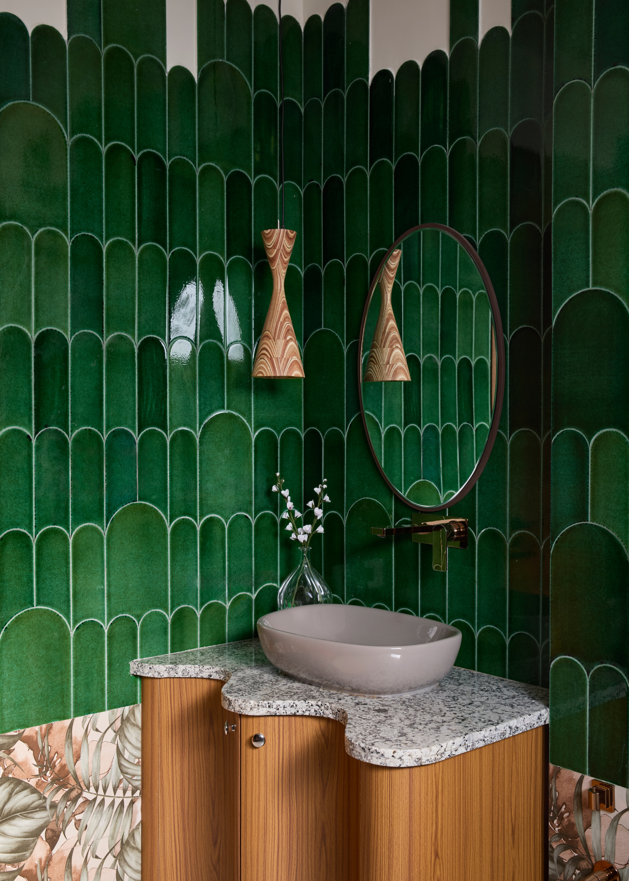 a contemporary powder room with green arched tiles that don't all meet the ceiling, with a curved basin and unique pendant light