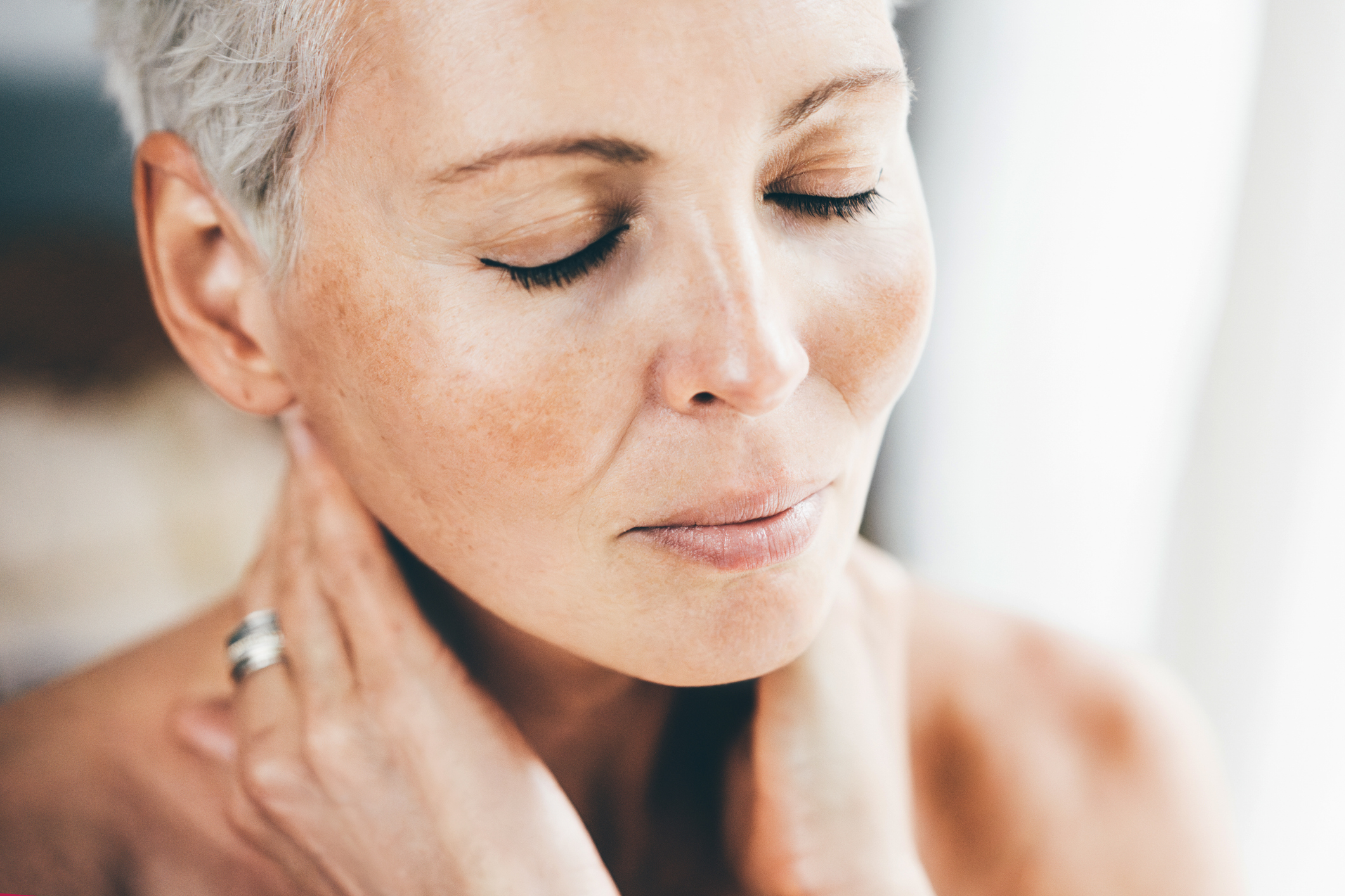 Portrait of a beautiful middle-aged woman touching her neck.
