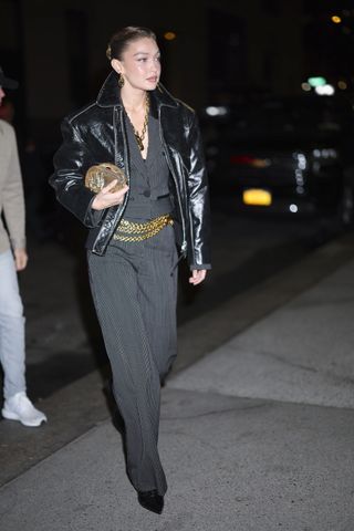 A photo of Hadid topping her striped suiting with a gold chain belt and pointy black booties.