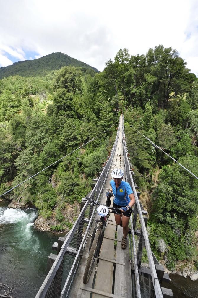 A rider crosses a high suspension bridge in the Trans Andes