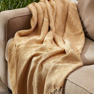 A yellow and white throw blanket on a gray couch