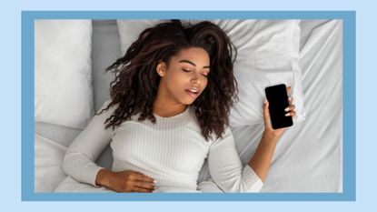 Asleep African American Woman Sleeping Through Alarm Clock On Phone Lying In Bed In Bedroom At Home In The Morning, Holding Smartphone. Oversleeping, Late For Work, Early Awakening Concept