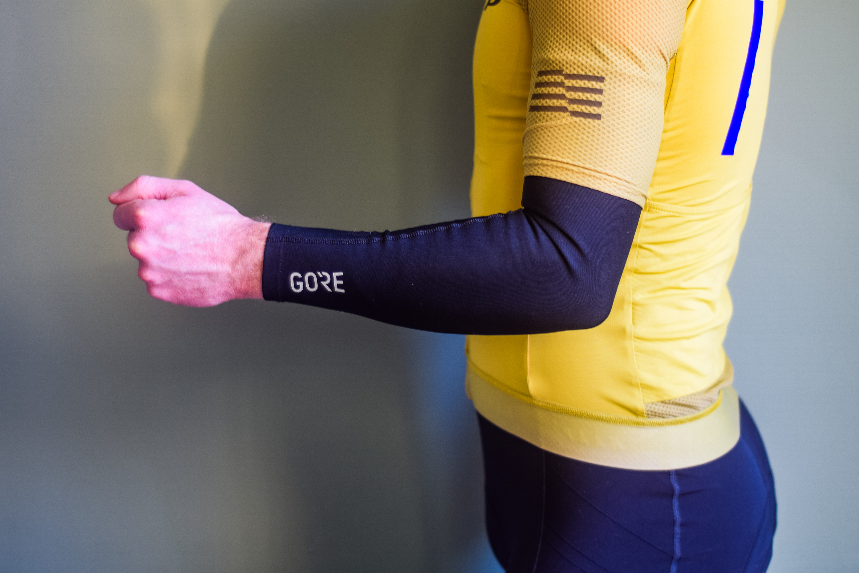 A man in a yellow cycling jersey wearing black arm warmers