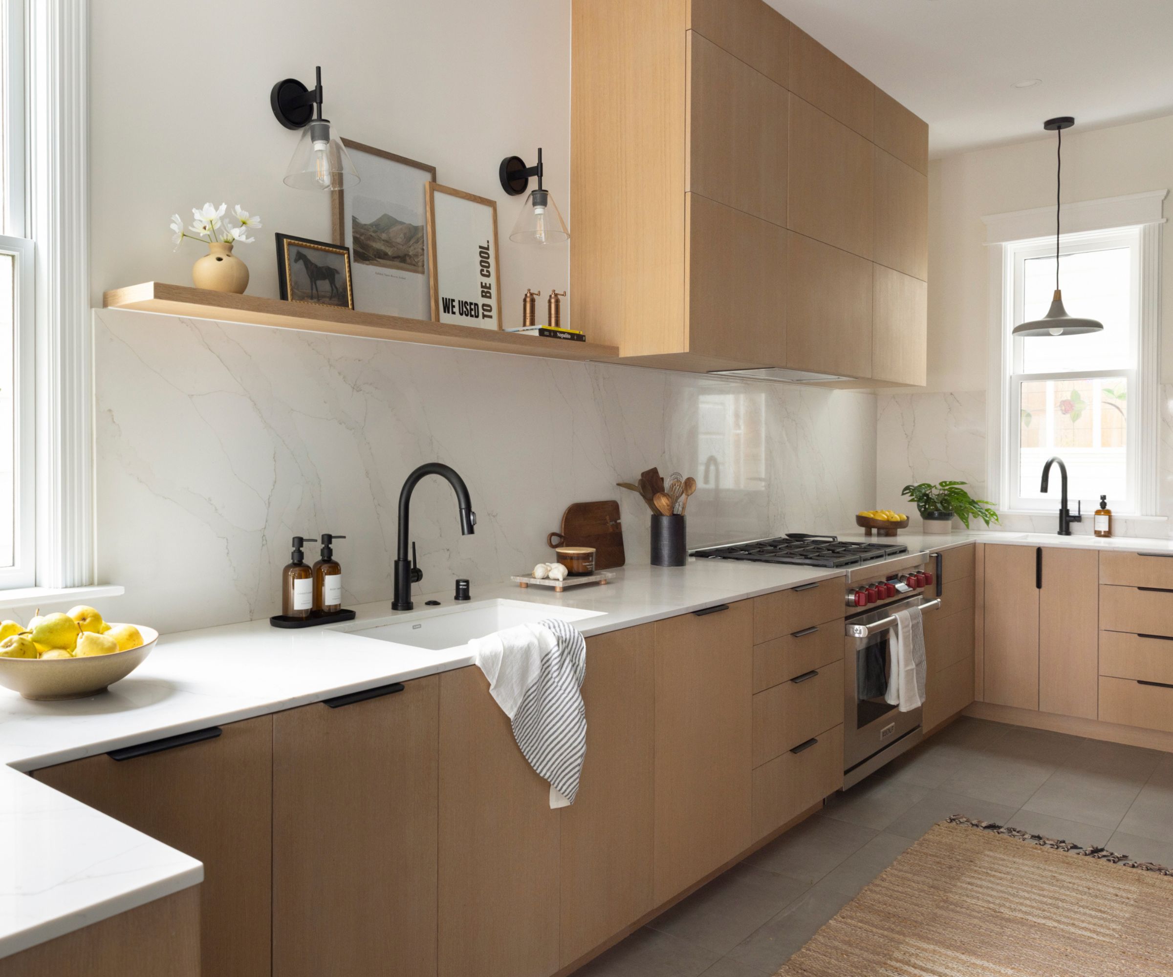A U-shaped kitchen with wooden cabinets and thin stone countertops