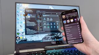 iPhone 16 in hand being held in front of Asus ROG Strix 17 display showing Phone Link transfering files