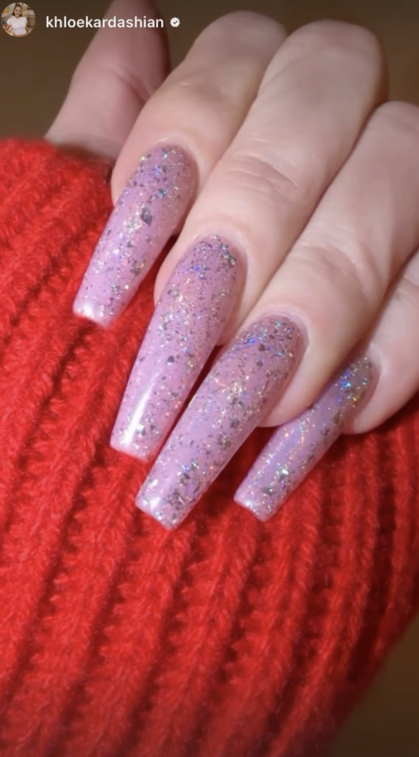 a woman wearing light pink nails with glitter