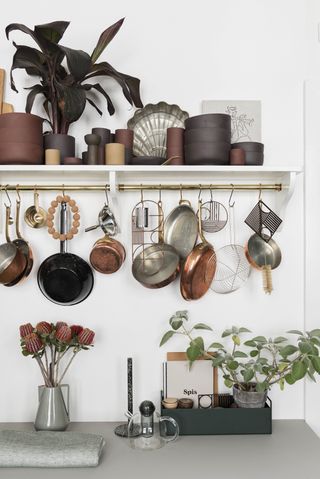 Copper accessories hung up on an open shelf in a kitchen