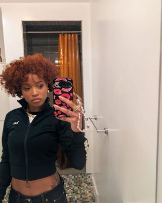 Keke palmer holding a phone taking a selfie in the mirror