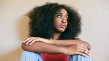 Woman feeling anxious, with her arms crossed over her legs