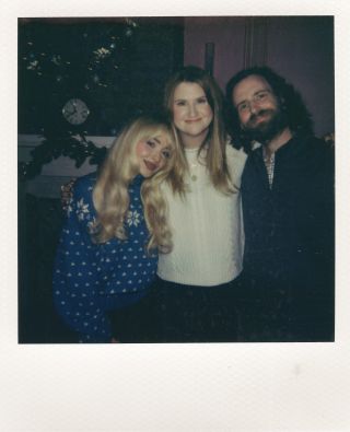 From left to right: Sabrina Carpenter, Jillian Bell and Kyle Mooney smiling together in a BTS photo for A Nonsense Christmas.