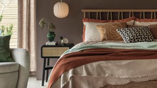 serene bedroom with neutral tones with earthy red accent colors on throws