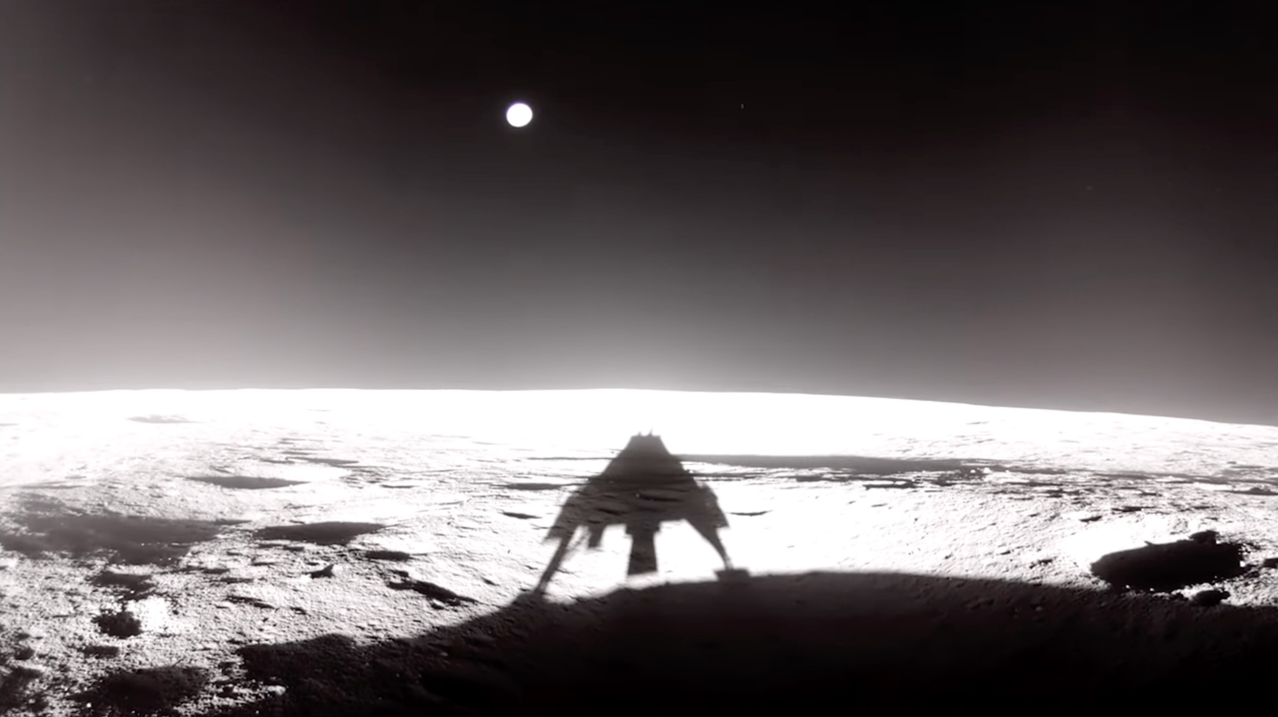 a robotic lander's shadow is visible on the lunar surface with the distant earth visible in the dark sky above