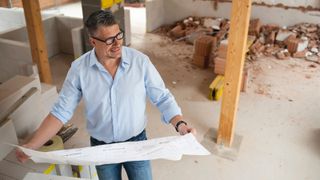 man holding floor plans in building site