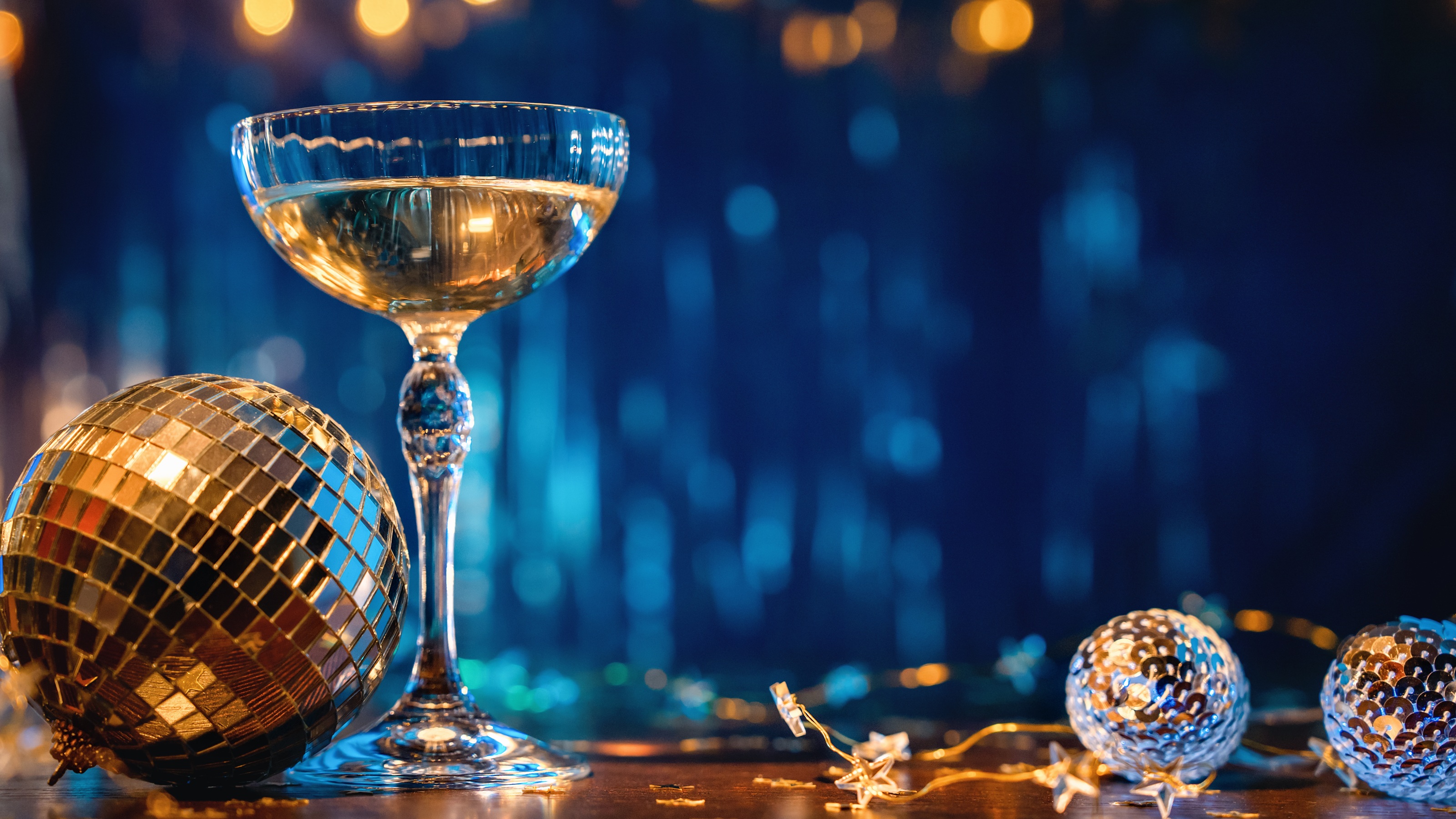 A glass of champagne and New Year's decor against a royal blue curtain background.