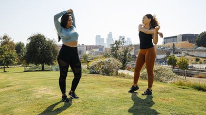 friends who are stretching in park before they exercise in the heat