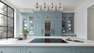 Blue kitchen with white worktop and vented extractor