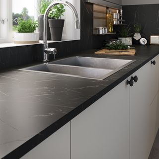 black worktop on white modern units with steel sink and chrome tap