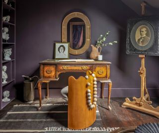 bedroom with dark walls desk/dressing table and classical busts on shelves