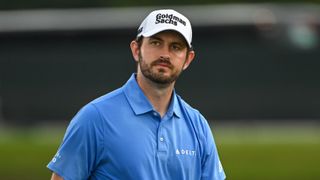 A close-up shot of Patrick Cantlay wearing a white Goldman Sachs cap and a blue Delta polo shirt
