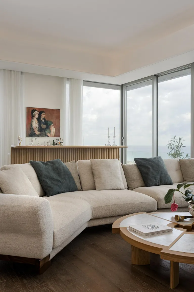 Sursock 14ème by Karim Nader Studio focusses on a curved cream sofa with cushions and a round table with different sizes pieces.