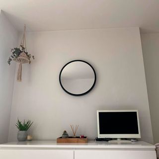 White wall with round mirror and white desk