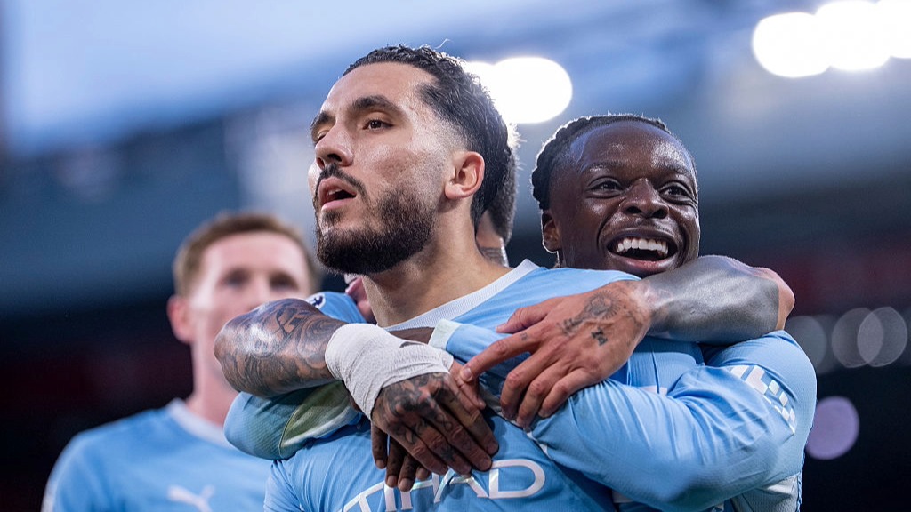 Rayan Cherki, hugged by Man City teammate Jeremy Doku, celebrates scoring against Liverpool.